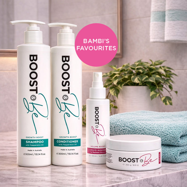 Boost & Be Growth Boost hair care bundle on a bathroom counter with a plant and towel in the background.