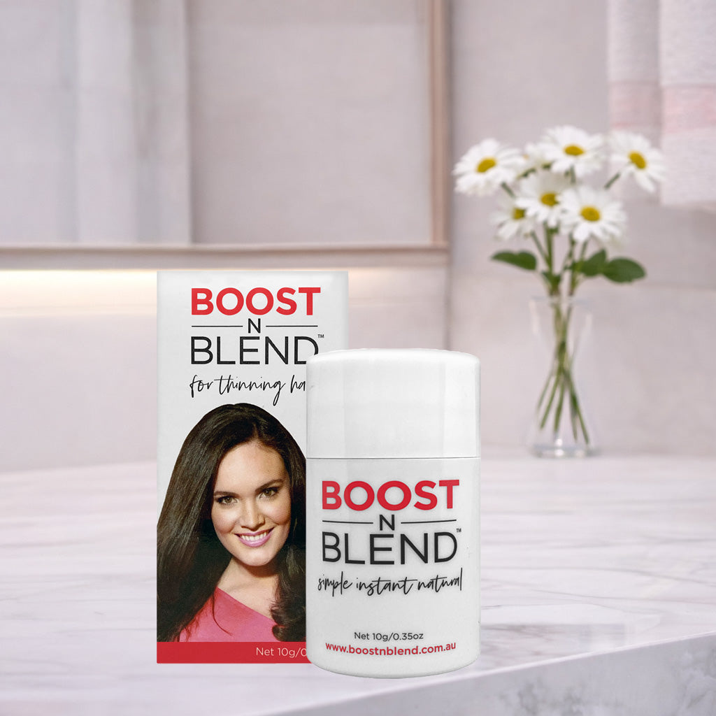Boost N Blend hair fibers 10g on a bathroom counter with flowers in the background