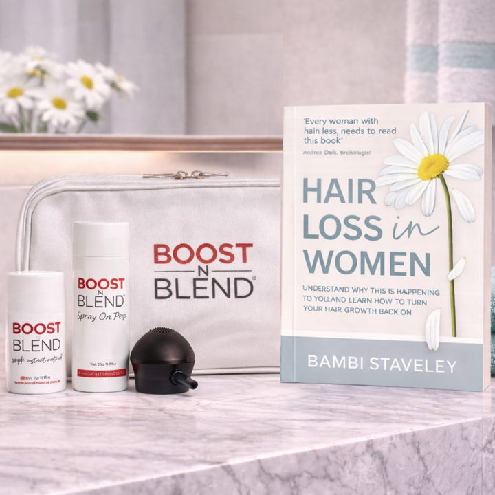 Boost N Blend hair loss products and a book titled 'Hair Loss in Women' by Bambi Staveley on a marble surface.
